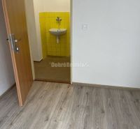 Na prenajom najlacnejšie komerčne priestory v Prievidzi. - Interiér obchodného priestoru s podlahou s dreveným dekorom a umývadlom pri žltých obkladoch.