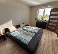 2iz byt v novostavbe Hlohovec Zľava!!! - Spálňa s posteľou, nočným stolíkom a podlahou s dreveným dekorom v 2-izbovom byte.