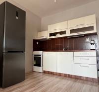 2iz byt v novostavbe Hlohovec Zľava!!! - Kuchyňa v 2-izbovom byte s podlahou s dreveným dekorom, bielou linkou a spotrebičmi.