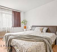 NA PREDAJ 6-IZBOVÝ RD S VEĽKÝM POZOMKOM, DOLNÝ ŠTÁL - Svetlá spálňa s pohodlnou posteľou, poličkou a podlahou s dreveným dekorom v rodinnom dome.