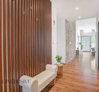 NA PREDAJ NADŠTANDARDNÁ 4-IZB. NOVOSTAVBA, DUN. KLÁTOV - Chodba rodinného domu s drevenou stenou, svetlou lavicou a dekoratívnymi prvkami.