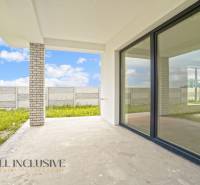 NA PREDAJ 4-IZBOVÁ NOVOSTAVBA, POVODA - Terasa rodinného domu v Dunajskej Strede na ulici Povoda s betónovou podlahou a veľkými oknami.