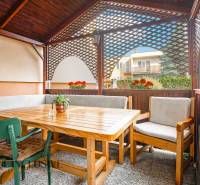 NA PREDAJ 5-IZBOVÝ POSCH. RODINNÝ DOM, DUNAJSKÁ STREDA - Terasa rodinného domu v Dunajskej Strede s dreveným sedením a kvetmi.