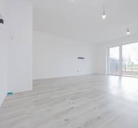 2 izb.BYT s POZEMKOM, PARKINGOM, Golf rezort Hrubá Borša - Svetlý interiér 2-izbového bytu s podlahou s dreveným dekorom a veľkými oknami.