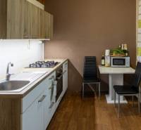 SLNEČNÝ A TICHÝ BYT S KRÁSNYM VÝHĽADOM - Kuchyňa 2-izbového bytu s podlahou s dreveným dekorom a jedálenským kútom.