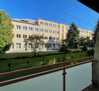 Na predaj 2,5 izbový byt v pôvodnom stave, 79 m2, Pod Sokolice, TN - Pohľad z balkóna 2-izbového bytu na ulici Pod Sokolice v Trenčíne na zeleň a budovu.