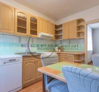 NA PREDAJ priestranný 4-izbový rodinný dom v Plaveckom Štvrtku - Kuchyňa v rodinnom dome má drevené skrinky, kachličkový obklad a jedálenský stôl.