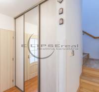 NA PREDAJ priestranný 4-izbový rodinný dom v Plaveckom Štvrtku - Predsieň rodinného domu so zrkadlovou skriňou, dverami a schodiskom s podlahou s dreveným dekorom.