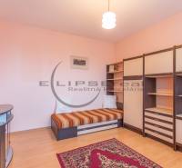 NA PREDAJ priestranný 4-izbový rodinný dom v Plaveckom Štvrtku - Izba s posteľou a nábytkom, podlaha s dreveným dekorom a svetloružové steny.