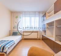 NA PREDAJ priestranný 4-izbový rodinný dom v Plaveckom Štvrtku - Izba v rodinnom dome s posteľou, skrinkami a podlahou s dreveným dekorom.