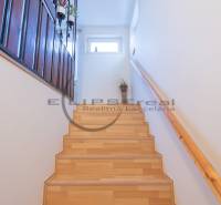 NA PREDAJ priestranný 4-izbový rodinný dom v Plaveckom Štvrtku - Schodisko so zábradlím, podlaha s dreveným dekorom, biele steny, črepník.