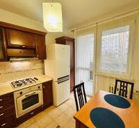 Prenajom 3 izb. bytu na Vajanskeho v NZ - Kuchyňa v 3-izbovom byte s drevenými skrinkami a jedálenským stolom s dvoma stoličkami.