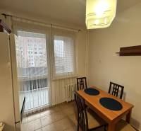 Prenajom 3 izb. bytu na Vajanskeho v NZ - Kuchyňa so stolom a stoličkami v 3-izbovom byte, dlažba na podlahe, výhľad cez okno.