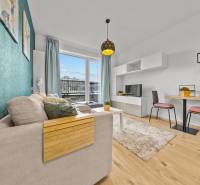 ZARIADENÝ 1-IZBOVÝ BYT, SLNEČNICE – IDEÁLNA INVESTÍCIA AJ BÝVANIE - Svetlá obývačka s pohovkou, jedálenským stolom a podlahou s dreveným dekorom v 1-izbovom byte.