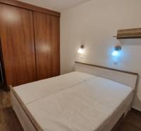 Na prenájom zariadený 3 izbový byt s balkónom Galanta- Mierová - Spálňa v 3-izbovom byte s posteľou, skriňou a podlahou s dreveným dekorom.