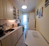 Pekný 2 izbový byt na Jadrovej ul. - Útulná kuchyňa v 2-izbovom byte s bielymi skrinkami a jedálenským stolom.