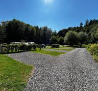 Zabehnutý multifunkčný rekreačný areál (kemp) Kuchyňa na predaj - Grótkovaný povrch s trávou a karavany v Rekreačných pozemkoch pri Kuchyni, obklopené stromami.