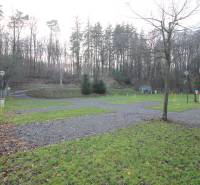 Zabehnutý multifunkčný rekreačný areál (kemp) Kuchyňa na predaj - Rekreačné pozemky v Kuchyni s trávnikmi a lesnou krajinou v pozadí.