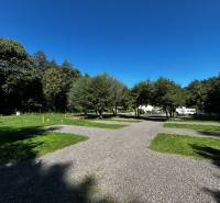 Zabehnutý multifunkčný rekreačný areál (kemp) Kuchyňa na predaj - Rekreačné pozemky v Kuchyni s karavanmi obklopené stromami a modrou oblohou.