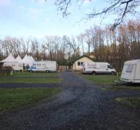 Zabehnutý multifunkčný rekreačný areál (kemp) Kuchyňa na predaj - Karavany a stany na rekreačných pozemkoch v Kuchyni obklopené stromami.