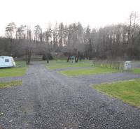 Zabehnutý multifunkčný rekreačný areál (kemp) Kuchyňa na predaj - Rekreačné pozemky v Kuchyni s karavanami, štrkovými cestami a lesným okolím.