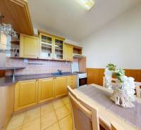 REZERVOVANÉ/ 3- izbový byt blízko centra mesta, Vrbové - Kuchyňa v 3-izbovom byte s drevenými skrinkami a bielym dekorom váz.