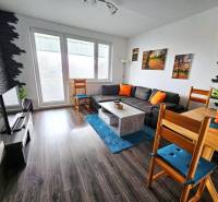 Útulný byt s loggiou a klimatizáciou, Rovniankova.Províziu neplatíte - Obývacia izba v 3-izbovom byte so sedačkou, TV a podlahou s dreveným dekorom.