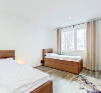 Mezonetový 3-izb. byt, Stará Ľubovňa, Popradská ulica - Spálňa s dvomi posteľami, stojanom na oblečenie a podlahou s dreveným dekorom v 3-izbovom byte.