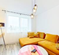 Mezonetový 3-izb. byt, Stará Ľubovňa, Popradská ulica - Obývacia izba v 3-izbovom byte s pohodlnou žltou pohovkou a podlahou s dreveným dekorom.