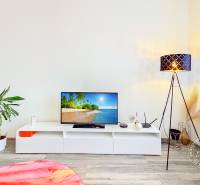 Mezonetový 3-izb. byt, Stará Ľubovňa, Popradská ulica - Obývacia izba s televízorom a stojatou lampou, podlaha s dreveným dekorom.