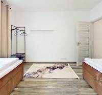 Mezonetový 3-izb. byt, Stará Ľubovňa, Popradská ulica - Spálňa v 3-izbovom byte s podlahou s dreveným dekorom, posteľami a stojanom na oblečenie.