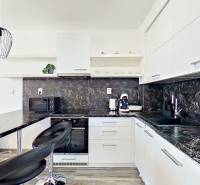 Mezonetový 3-izb. byt, Stará Ľubovňa, Popradská ulica - Kuchyňa v 3-izbovom byte s tmavou pracovnou doskou a štýlovým osvetlením.