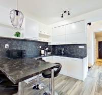 Mezonetový 3-izb. byt, Stará Ľubovňa, Popradská ulica - Kuchyňa v 3-izbovom byte s podlahou s dreveným dekorom a tmavým pracovným pultom.