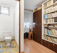 Na predaj 4-izb. rodinný dom s garážou, Okoč - Toaleta s dlažbou vedľa izby s knihovnicou a podlahou s dreveným dekorom v rodinnom dome.