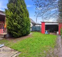 Na predaj 4-izb. rodinný dom s garážou, Okoč - Záhrada rodinného domu na ulici Okoč v meste Veľký Meder, s červenou garážou.