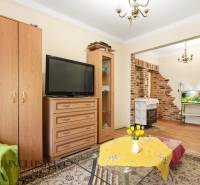 Na predaj 4-izb. rodinný dom s garážou, Okoč - Obývacia izba v rodinnom dome s tehlovými detailmi a podlahou s dreveným dekorom.