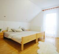 EXKLUZÍVNE / RODINNÝ DOM NA PREDAJ V OBCI SÚĽOV - Spálňa s dreveným dekorom, pribalenými vankúšmi a veľkým oknom v rodinnom dome.