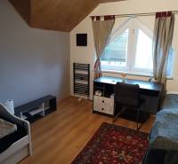 Na predaj rodinný dom Orovnica - Izba v rodinnom dome s podlahou s dreveným dekorom, písací stôl, posteľ a koberec.