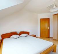 RIVERS | Viacgeneračný zrekonštruovaný rodinný dom v Ivanke pri Dunaji - Spálňa v rodinnom dome s posteľou, vstavanou skriňou a podlahou s dreveným dekorom.