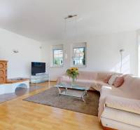 RIVERS | Viacgeneračný zrekonštruovaný rodinný dom v Ivanke pri Dunaji - Obývacia izba v rodinnom dome s kachľovou pecou, rohovou sedačkou a podlahou s dreveným dekorom.