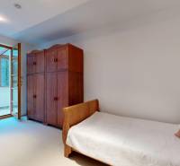 Veľkometrážny byt na Slavíne s výhľadom na mesto - Spálňa s čalúnenou posteľou, drevenou skriňou a balkónom na ulici Havlíčkova.