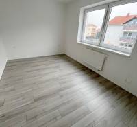 Na predaj 2 izb. byt s balkónom blízko centra, Chorvátsky Grob - Prázdna izba v 2-izbovom byte, s podlahou s dreveným dekorom a veľkým oknom.