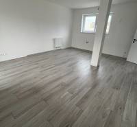 Na predaj 2 izb. byt s balkónom blízko centra, Chorvátsky Grob - Prázdna izba s podlahou s dreveným dekorom v 2-izbovom byte, biele steny, dve okná.
