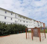 Na predaj 2 izb. byt s balkónom blízko centra, Chorvátsky Grob - Bytovky na Školskej ulici v Chorvátskom Grobe s detským ihriskom v popredí.