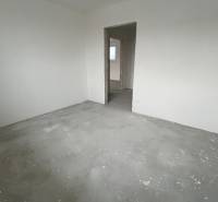 Na predaj 3 izb. byt s balkónom blízko centra, Chorvátsky Grob - Prázdna miestnosť v 3-izbovom byte s betónovou podlahou a nedokončenými stenami.