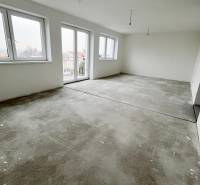 Na predaj 3 izb. s 2 balkónmi a panoramatickým výhľadom - Priestranná izba v 3-izbovom byte s betónovou podlahou a veľkými oknami.