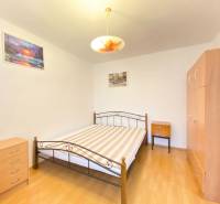 NA PRENÁJOM 2-IZBOVÝ BYT, NÁRODNÁ TRIEDA - Spálňa v 2-izbovom byte s posteľou, skriňou a podlahou s dreveným dekorom.