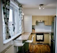 Prenájom moderný a svetlý 3-izbový byt v atraktívnej lokalite - Kuchyňa v 3-izbovom byte s barovým pultom, podlahou s dreveným dekorom a veľkým oknom.