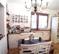 Rodinný dom, Vršatské Podhradie, okres Ilava - Jedáleň v rodinnom dome s bielym nábytkom, obrázkami na stene a ozdobným lustrom.
