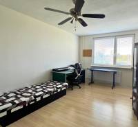 3-izbový byt na prenájom, 87 m2, Beethovenova ul. Nitra - Izba v 3-izbovom byte s posteľou, stolom a podlahou s dreveným dekorom.